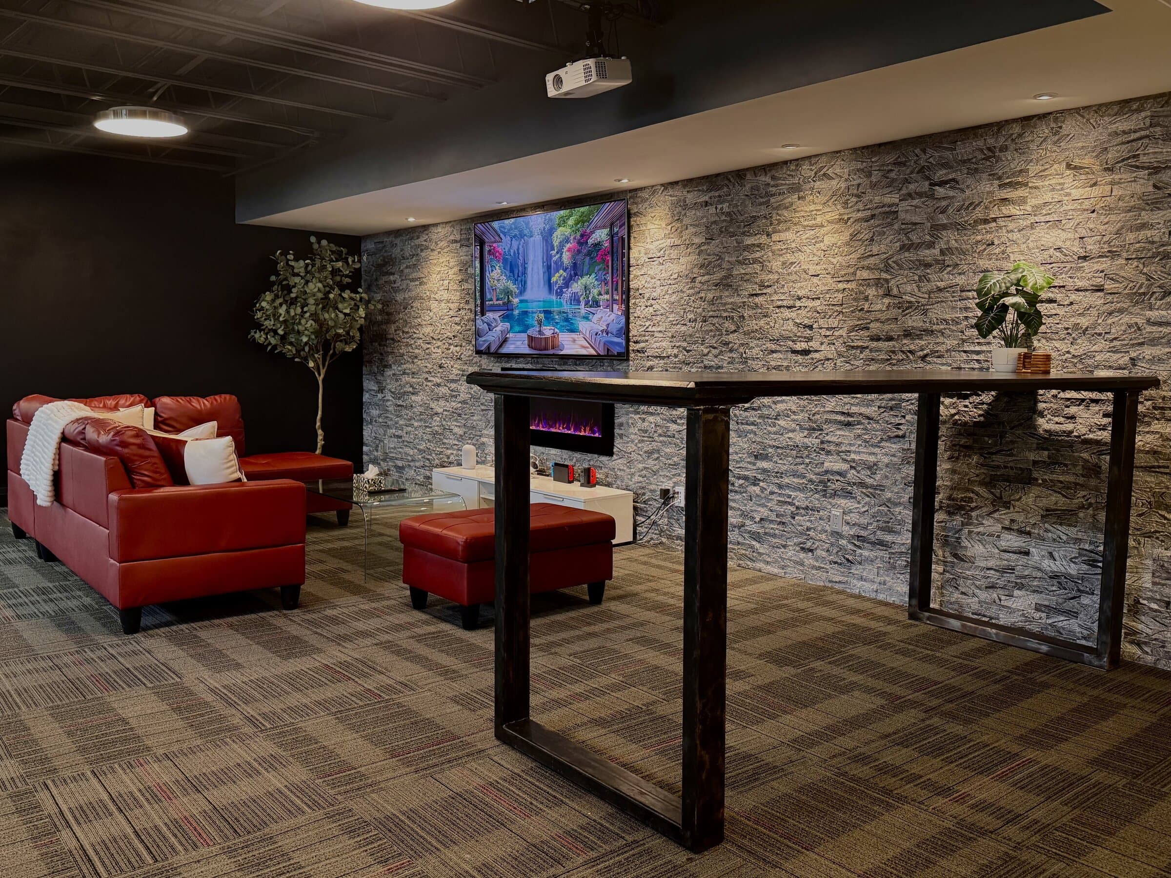 The members’ lounge with a red sectional sofa, a stone feature wall and a high work table